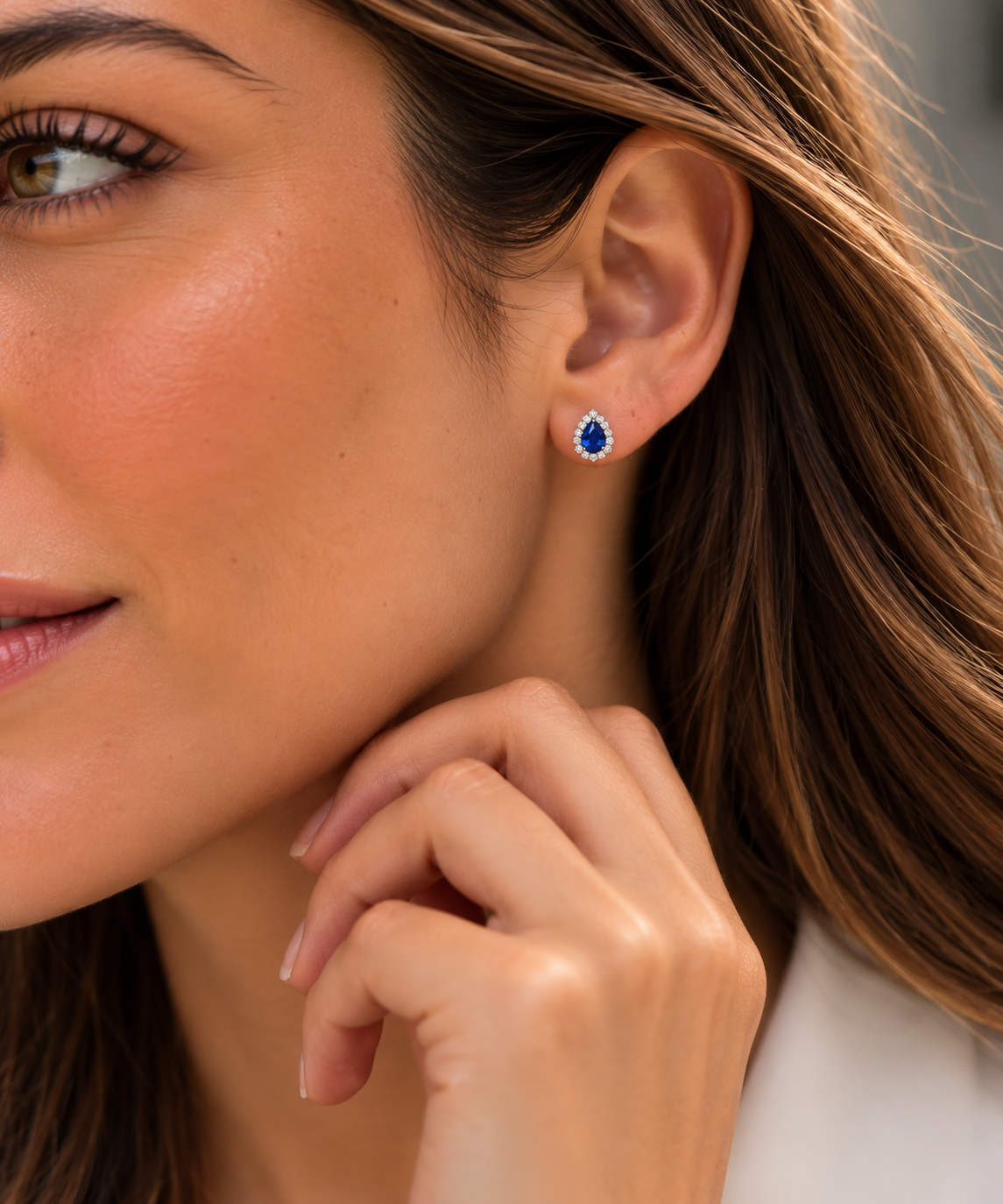 Modelo usando un arete Coral Azul con piedra azul en forma de gota rodeada de piedras transparentes.