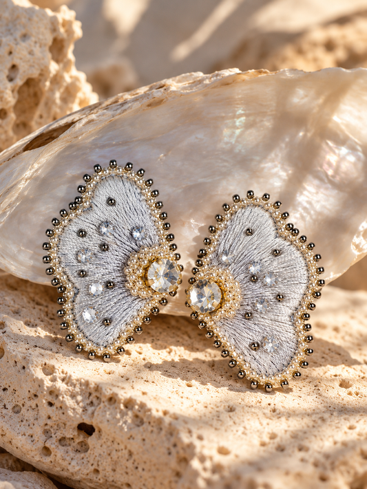 Aretes Curazao en forma de flor en color plateado. Elaborados con hilo de seda, cristales y mostacillas