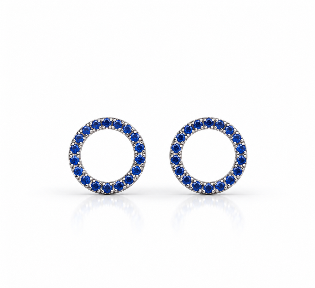 Par de aretes Mona Azul con centro abierto y contorno circular de piedras azules, sobre fondo blanco.