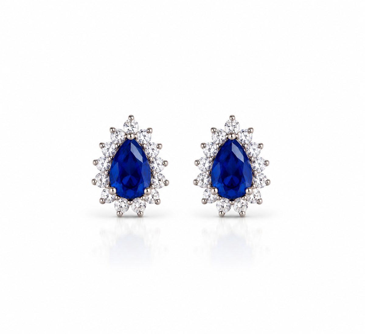 Aretes Coral Azul con piedras azules en forma de gota y halo de piedras transparentes, sobre fondo blanco.