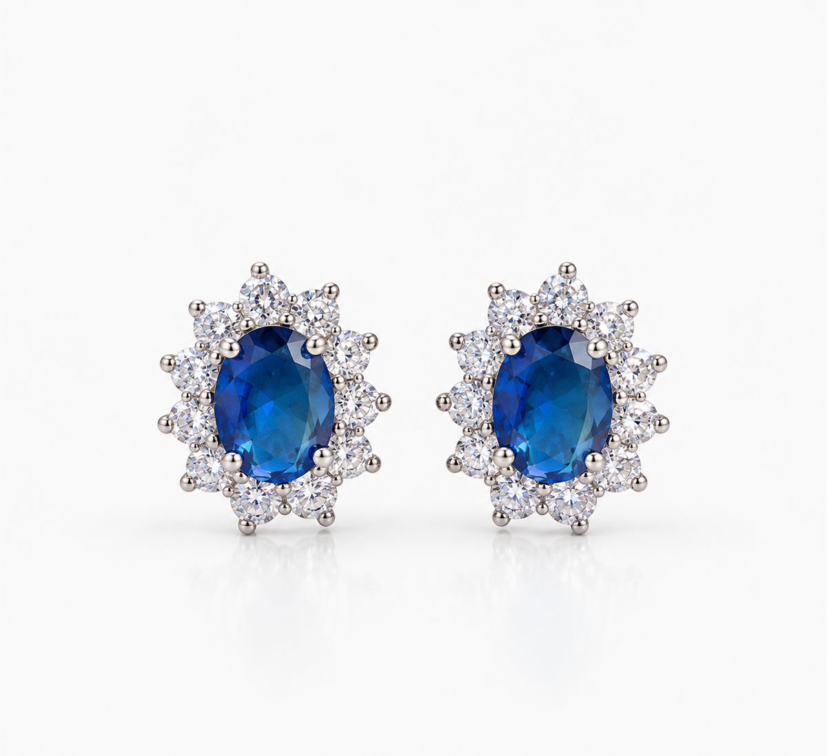 Aretes Aya Azul con piedra central ovalada azul, rodeada de pequeñas piedras transparentes en una montura de tono plateado.