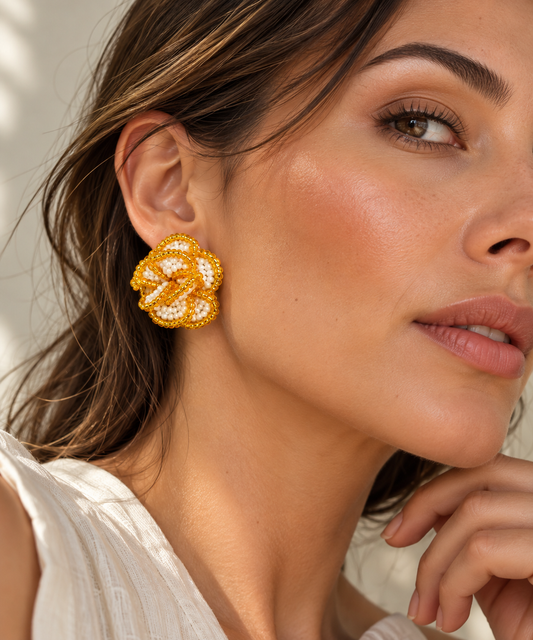 Modelo con arete Crisantemo de SALÁ en forma de flor, con cuentas blancas y bordes dorados.
