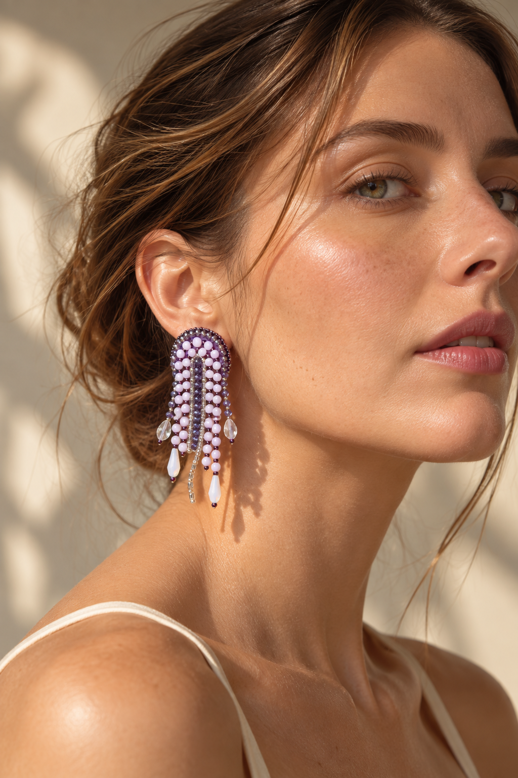 Modelo con un arete Medusa lila con flecos de cuentas y colgantes en forma de gota.
